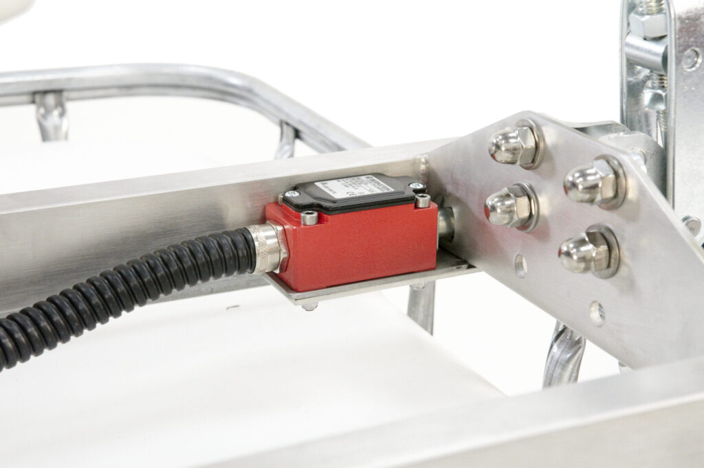 Red safety interlock switch mounted on the stainless steel bridge of a US Mixers IBC mixer